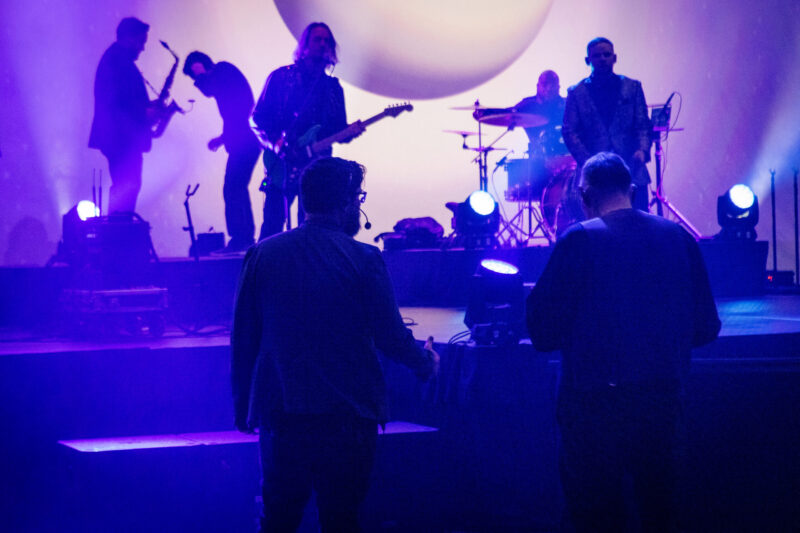 hazy purple light as musicians prepare backline instruments with avad3 crew members in foreground