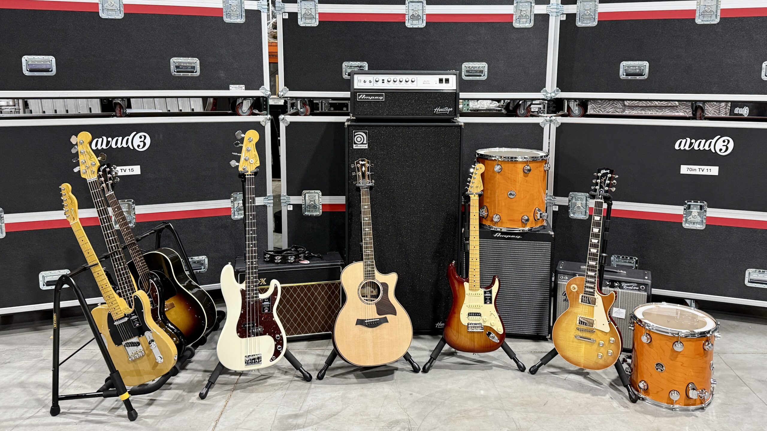 Lineup of common backline instruments - guitars, drums - in front of road cases