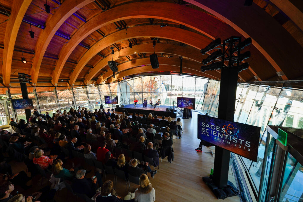 flown speakers are shown around an audience facing a conference stage